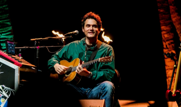 A man wearing green jacket playing a guitar
