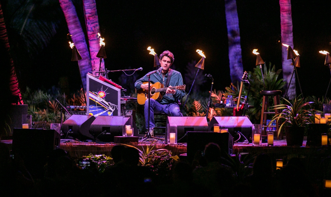A man performing on stage using a guitar