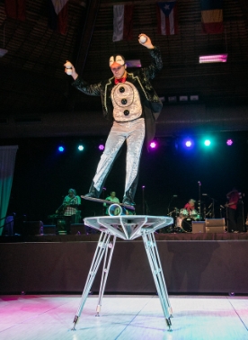 A man wearing black suit balancing on top of the table
